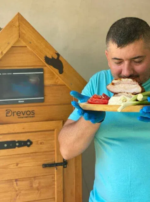 Client gustând carne afumată lângă afumătoarea lui